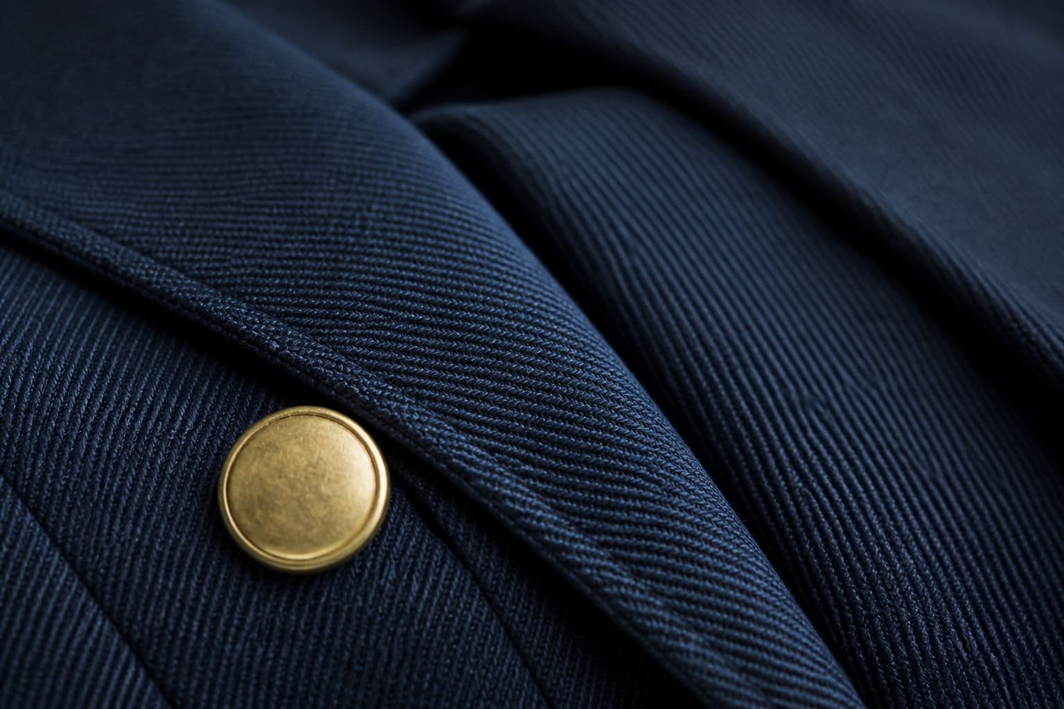 Close-up of navy uniform fabric with visible weave and a brass button